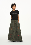 Person wearing a black 'FRIED RICE' t-shirt and long green skirt on a white background