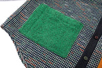 Textured green square patch on a patterned fabric background