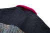 Close-up of a dark fabric surface with a textured pattern and a magenta collar.