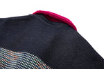 Close-up of a dark fabric surface with a textured pattern and a magenta collar.